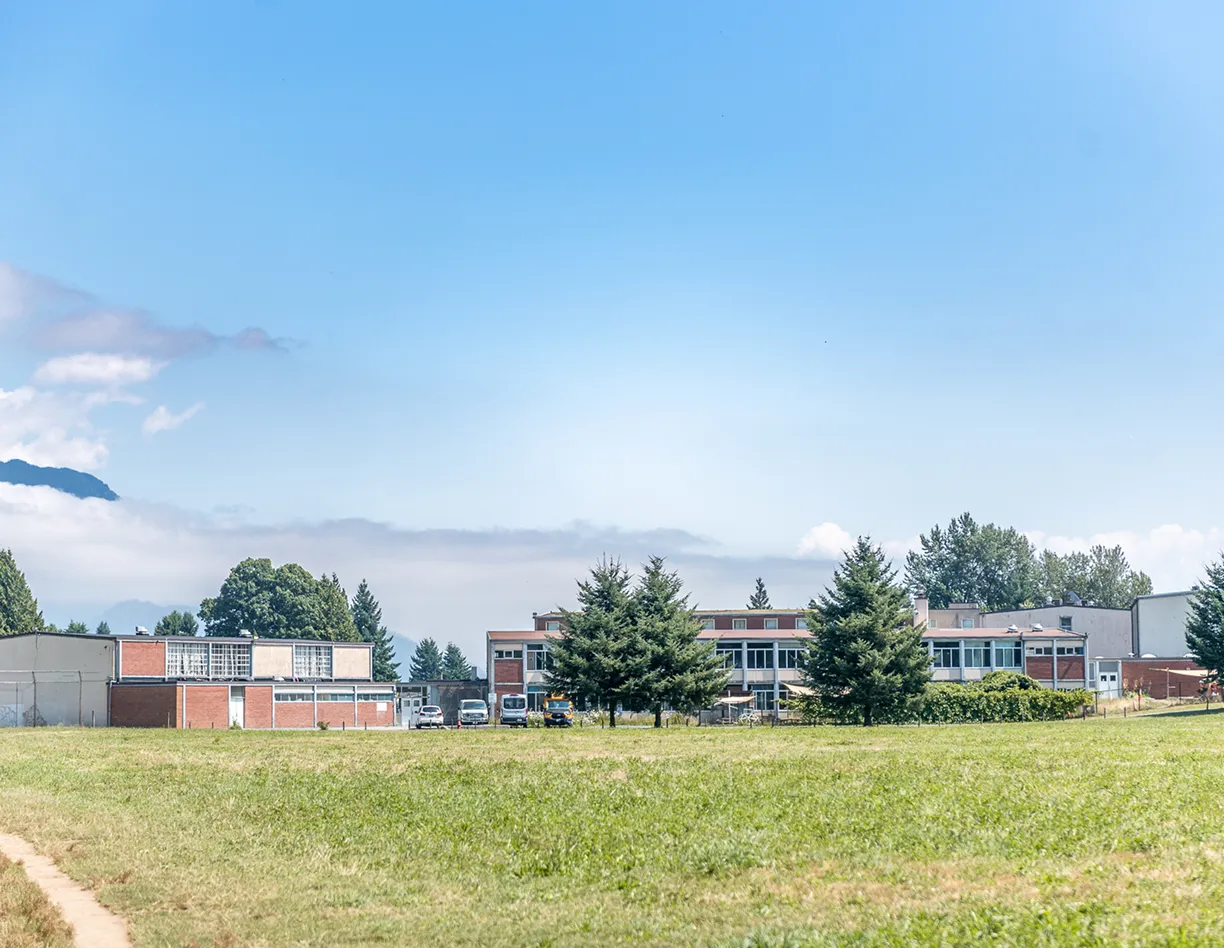 A grassy field with buildings in the background.