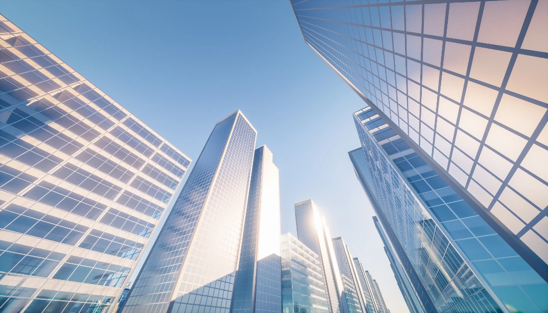 Low-angle view of modern glass skyscrapers under a clear blue sky.
