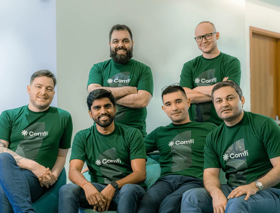 A group of 6 people smiling and wearing green shirt. 2 Standing at the back and 4 sitting in front.