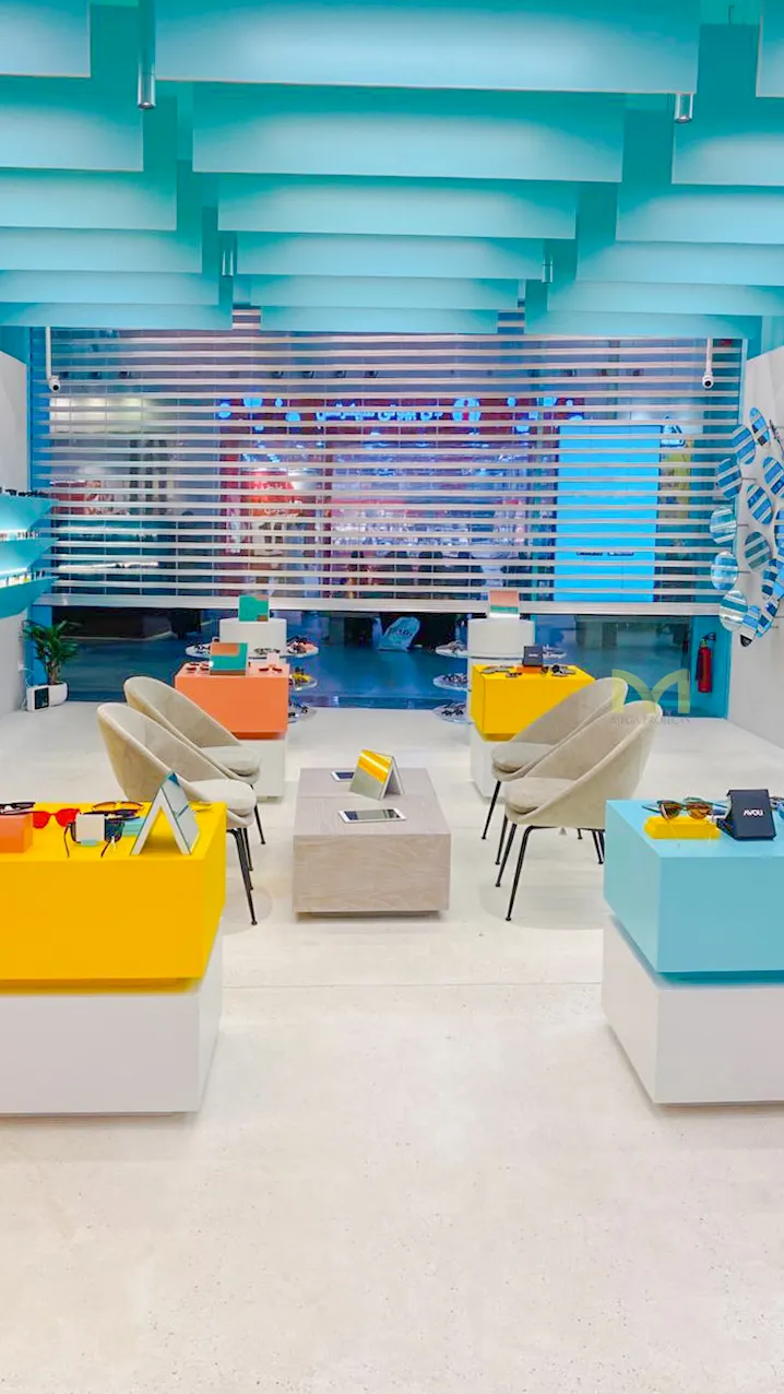 Bright modern retail store interior with colorful display tables, sunglasses, and cozy chairs.