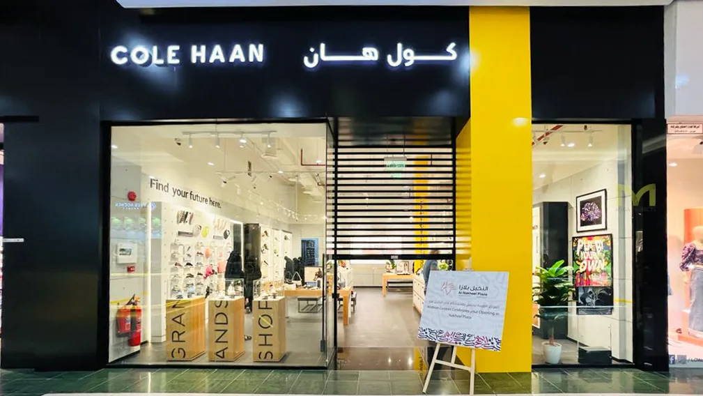 Front view of COLE HAAN store with black and yellow design in a shopping mall.