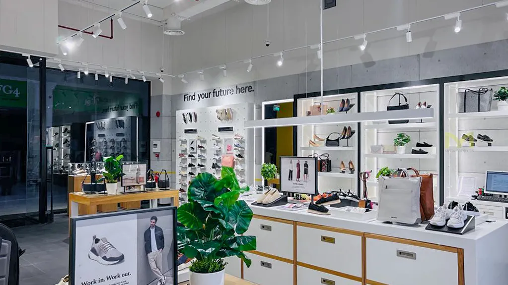 Modern retail store interior displaying shoes, handbags, and promotional material in bright, organized space.