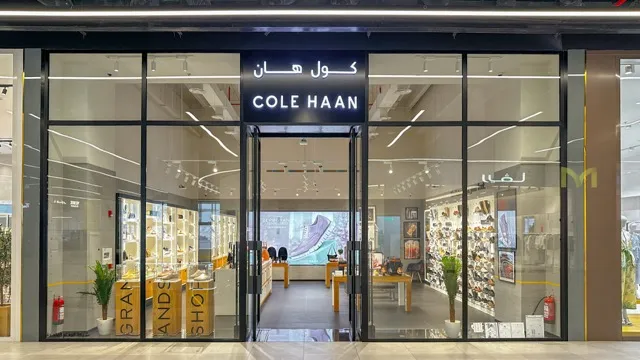 Exterior view of a Cole Haan retail store with glass doors and shoe displays inside.