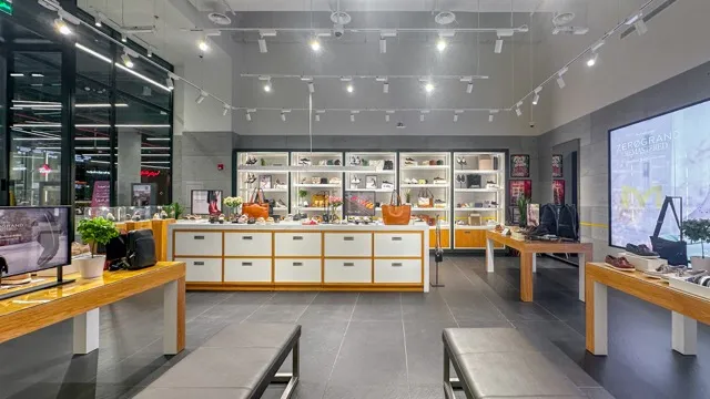 Modern retail store interior with shelves and tables displaying bags, shoes, and accessories.