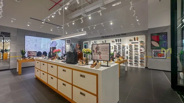Modern retail store interior with shoes, handbags, and a central white display counter with flowers.