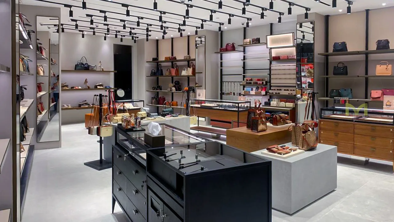 Modern luxury boutique interior with shelves and counters displaying handbags, wallets, and accessories.