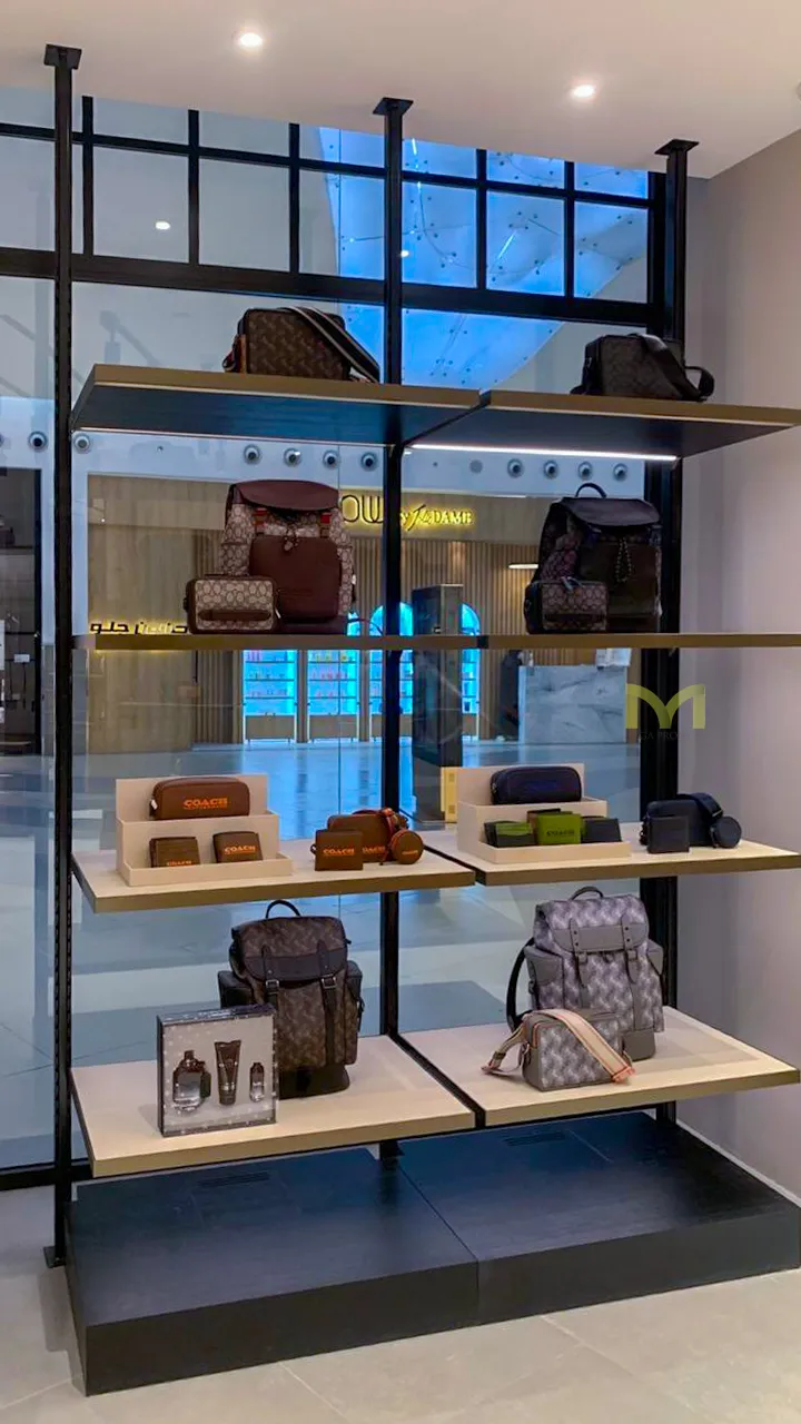 Retail shelf with designer backpacks, wallets, and small leather goods in a store display.