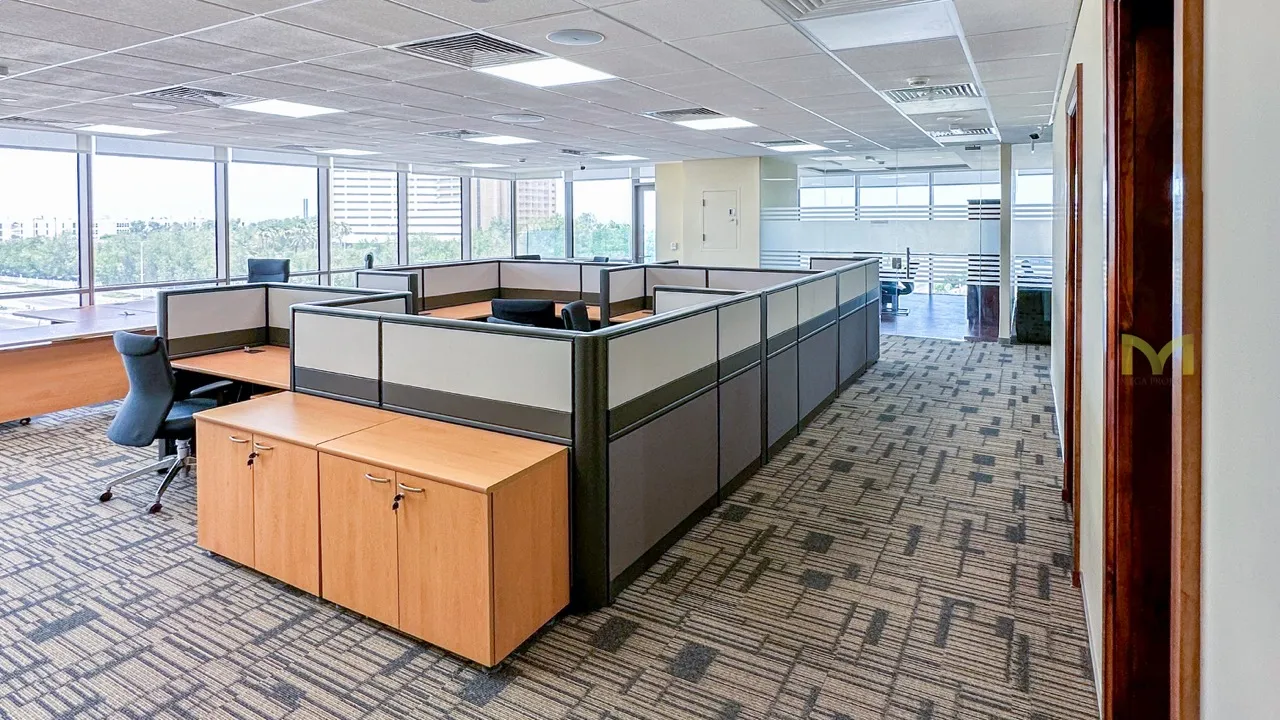 Modern office space with cubicles, office chairs, wooden cabinets, and large windows with city views.