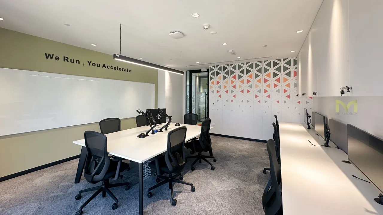 Modern office room with white tables, black chairs, computer monitors, and geometric wall design.