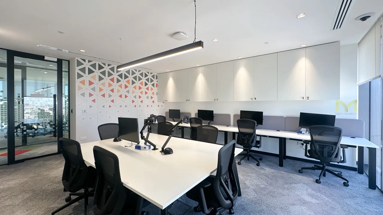 Modern office with white desks, black chairs, computer monitors, and geometric wall decor.