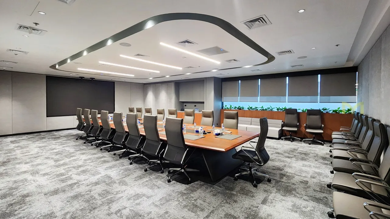 Spacious modern conference room with large wood table, high-back chairs, carpet, and window blinds.