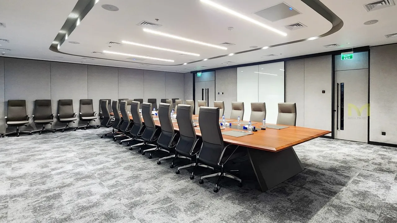 Modern conference room with a large wooden table and black and beige office chairs around it.