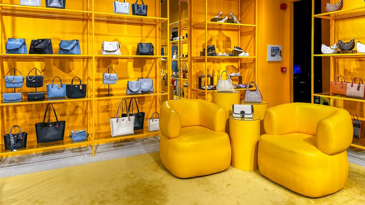 Yellow retail space with shelves of handbags and shoes and two modern yellow lounge chairs.