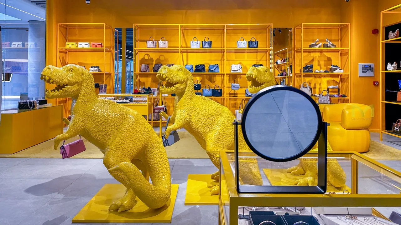 Yellow dinosaur sculptures holding handbags inside a bright yellow luxury retail store.