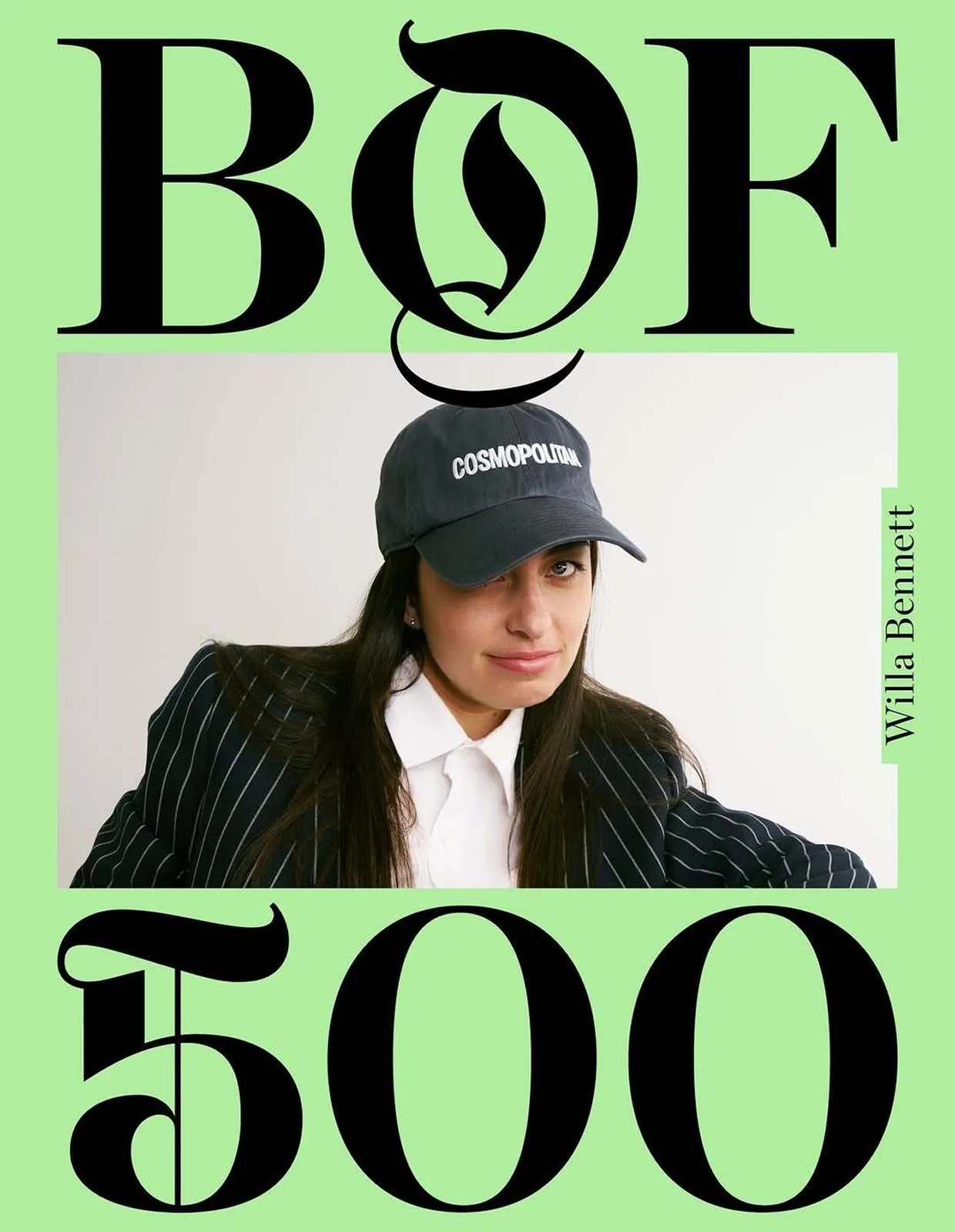 Portrait of a woman wearing a black pinstripe blazer, white shirt, and black cap with 'COSMOPOLITAN' text.