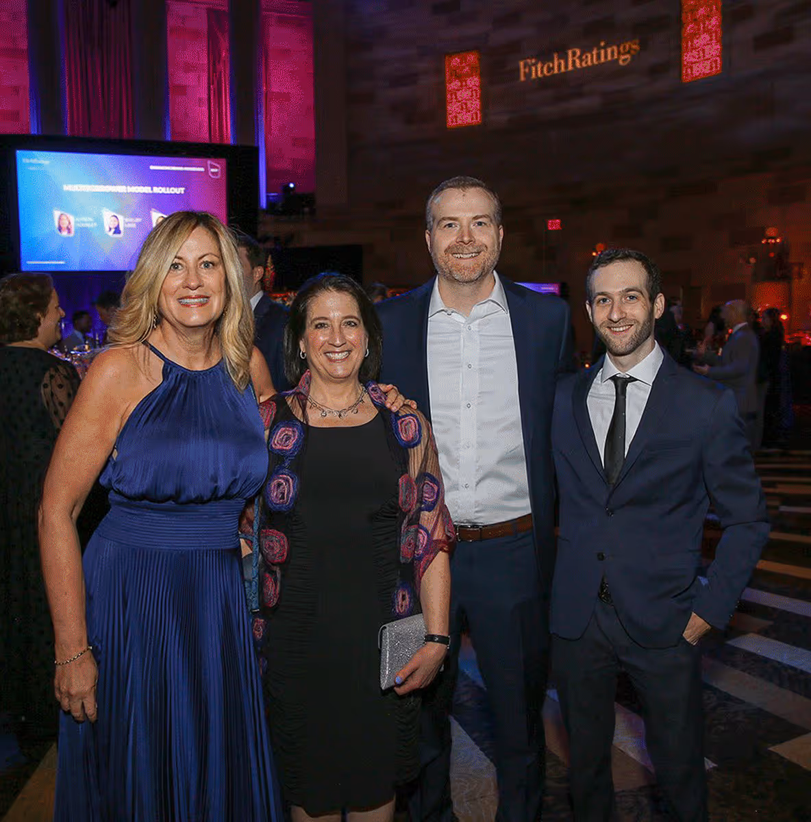 Two women and two men dressed in formal attire smiling at a Fitch Ratings event.