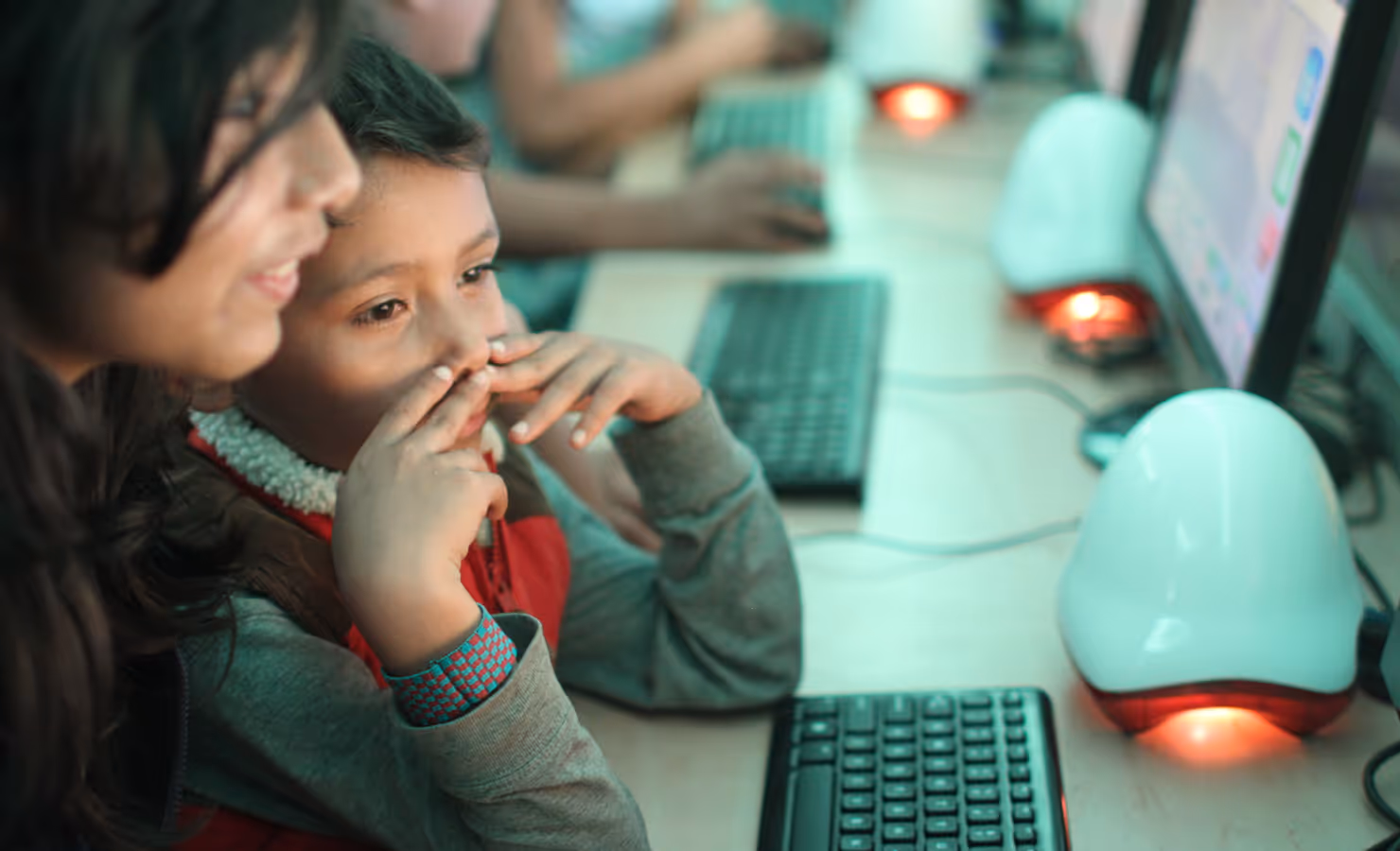 A young boy and girl closely looking at a computer screen together in a classroom setting.