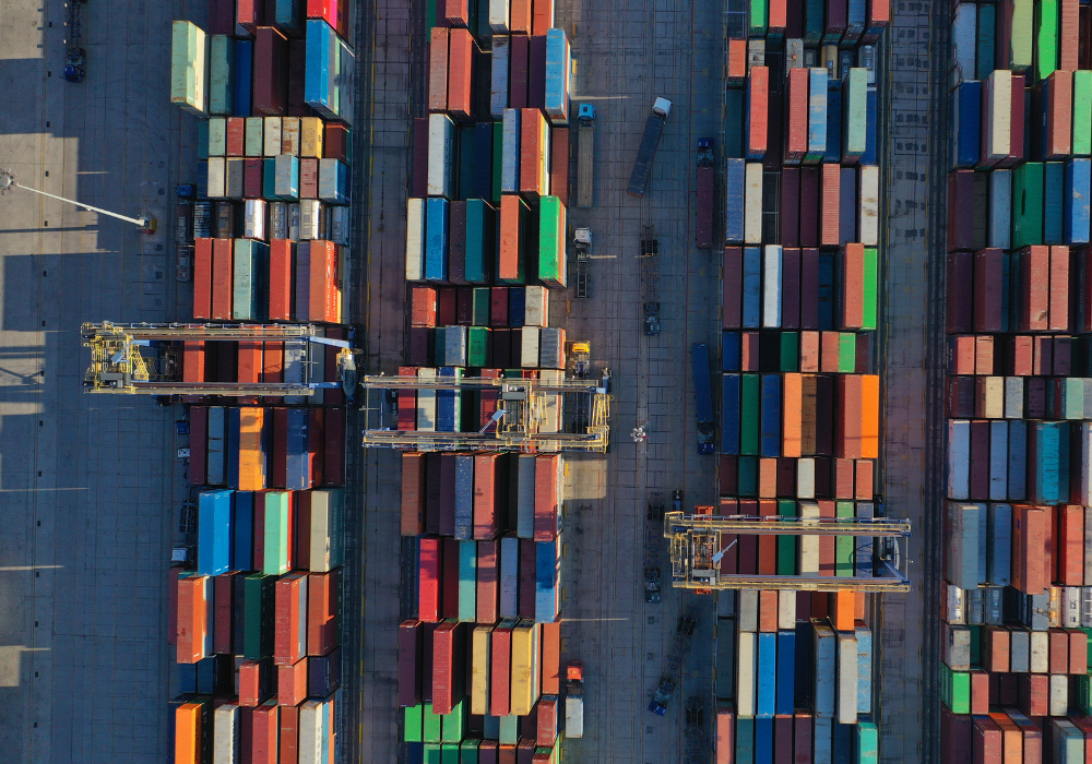 Aerial view of a shipping container port with rows of colorful containers and cranes.