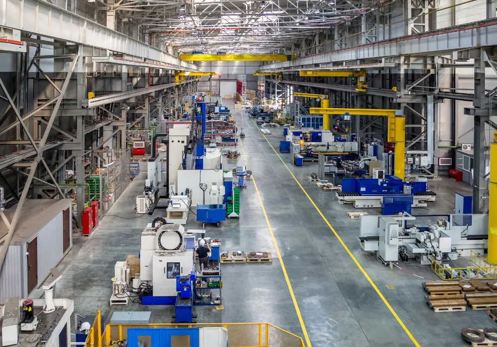 Large modern manufacturing plant with industrial machines and overhead cranes