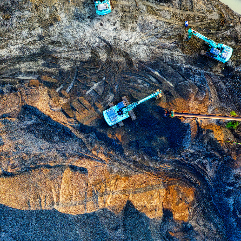 Aerial view of a mining site with blue excavators moving earth and gravel.