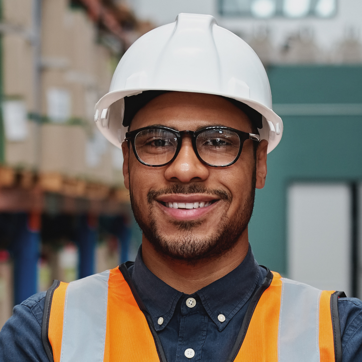 Smiling logistics worker in a white hard hat and hi-vis vest