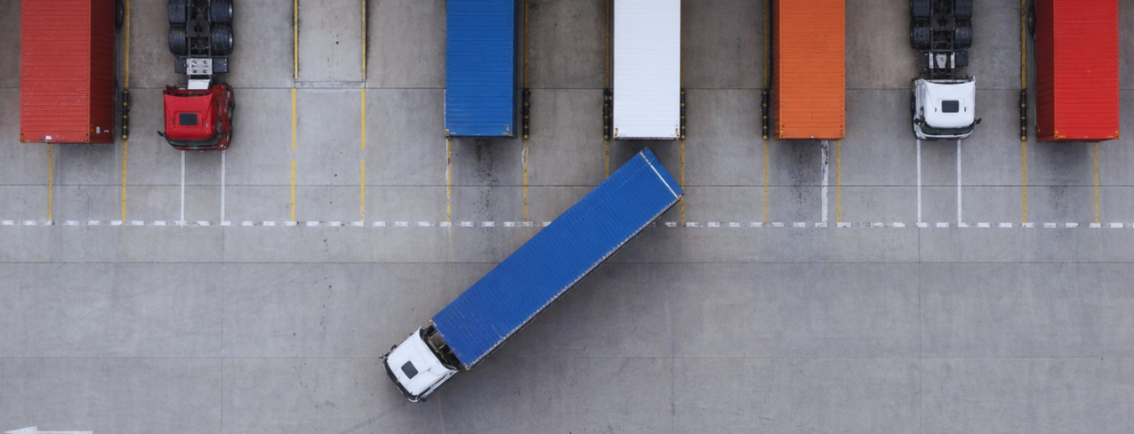 Aerial view of a semi-truck pulling out of a loading bay between parked trailers