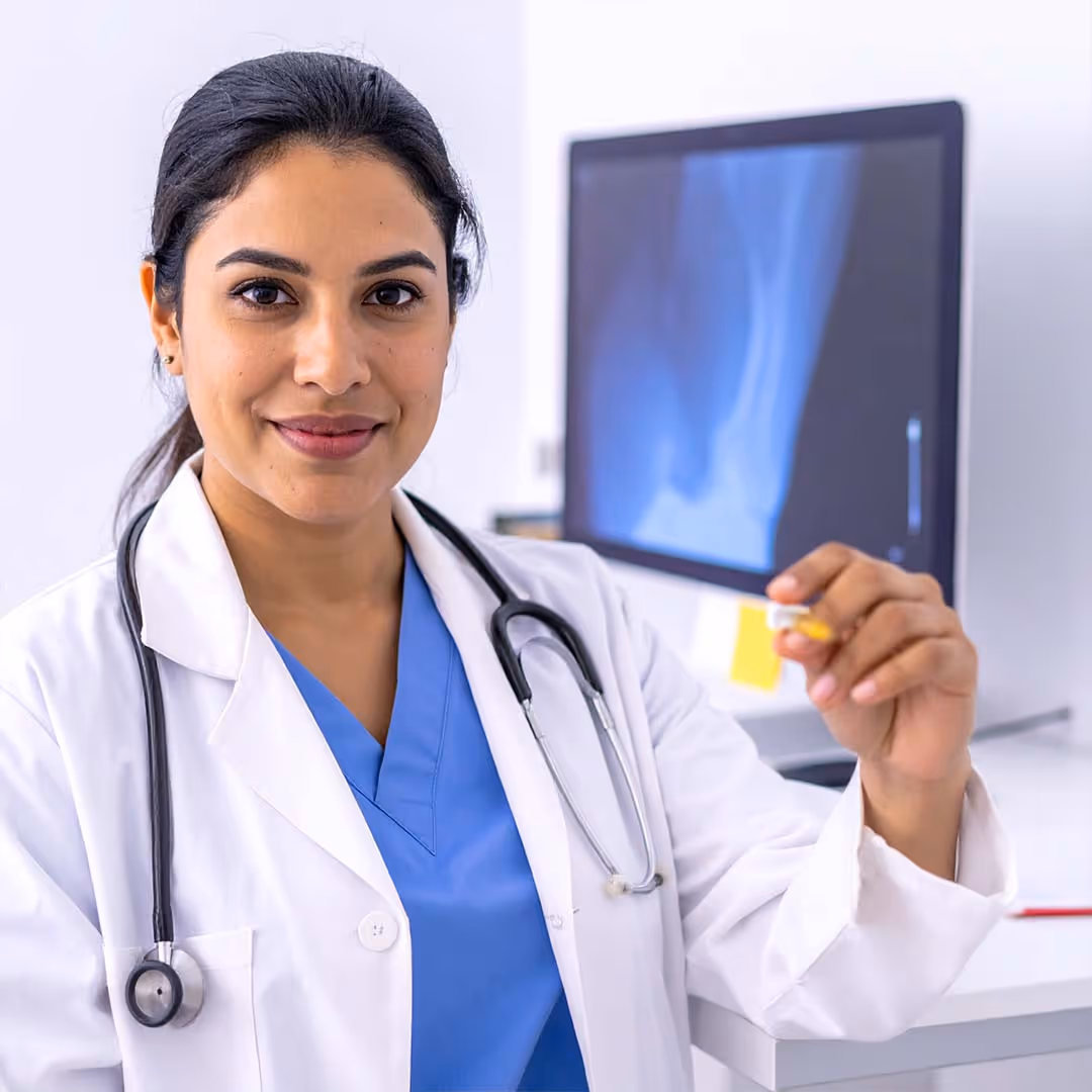 Orthopädin steht vor einem Bildschirm und hält einen Zettel in die Luft.