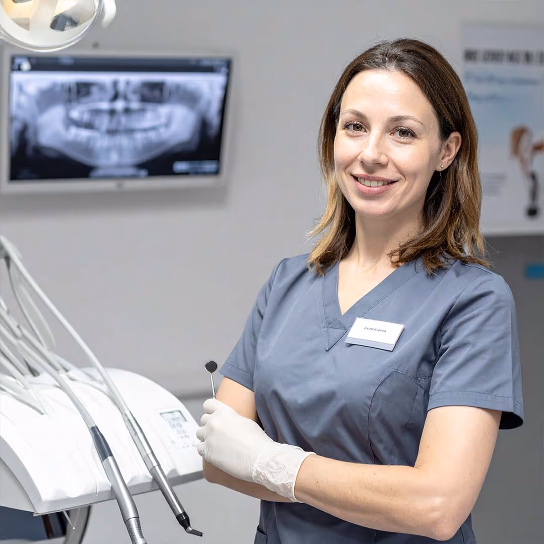 Zahnärztin steht in ihrer Praxis und lächelt in die Kamera