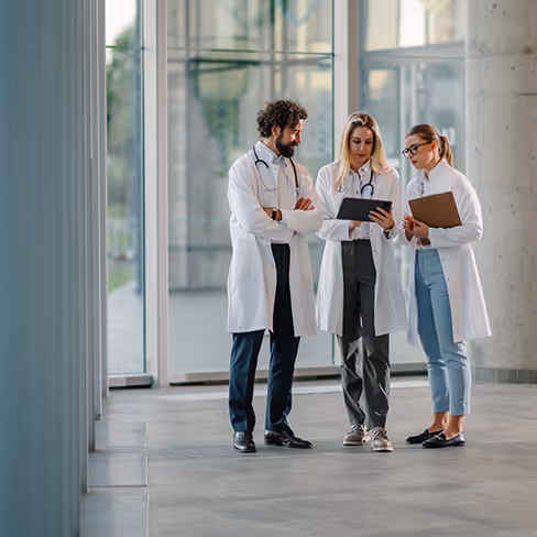 Drei Ärzte stehen beisammen und unterhalten sich über die neue Website von einem sympathischen Arzt