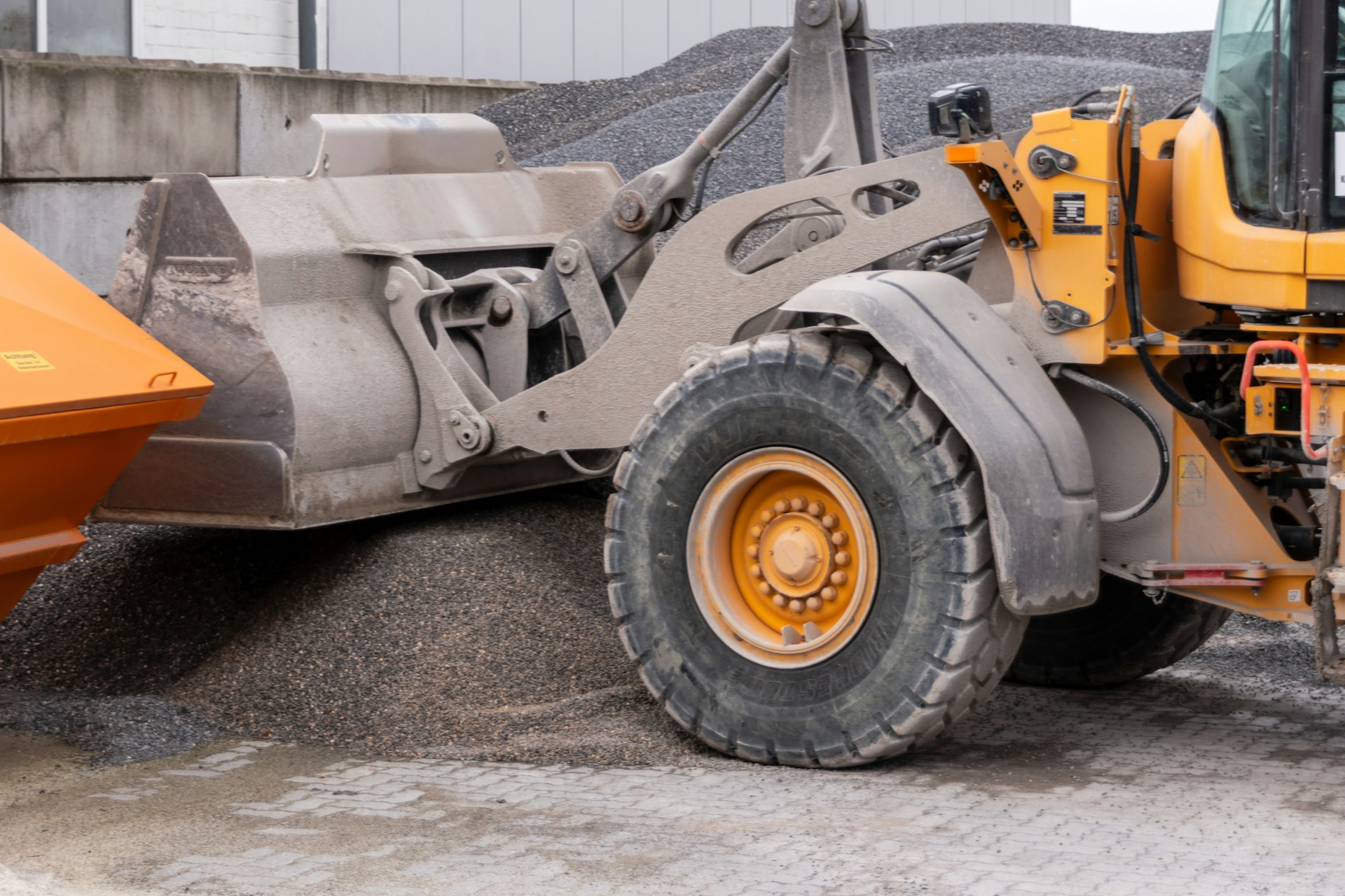 Close-up of a yellow front loader construction vehicle with a large bucket filled with gravel.