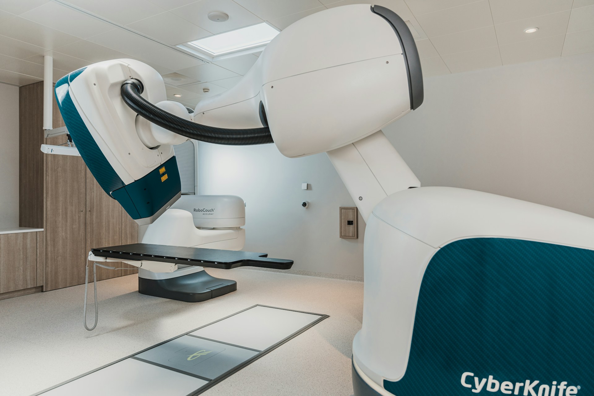 CyberKnife robotic radiosurgery system with adjustable patient couch in a clean treatment room.