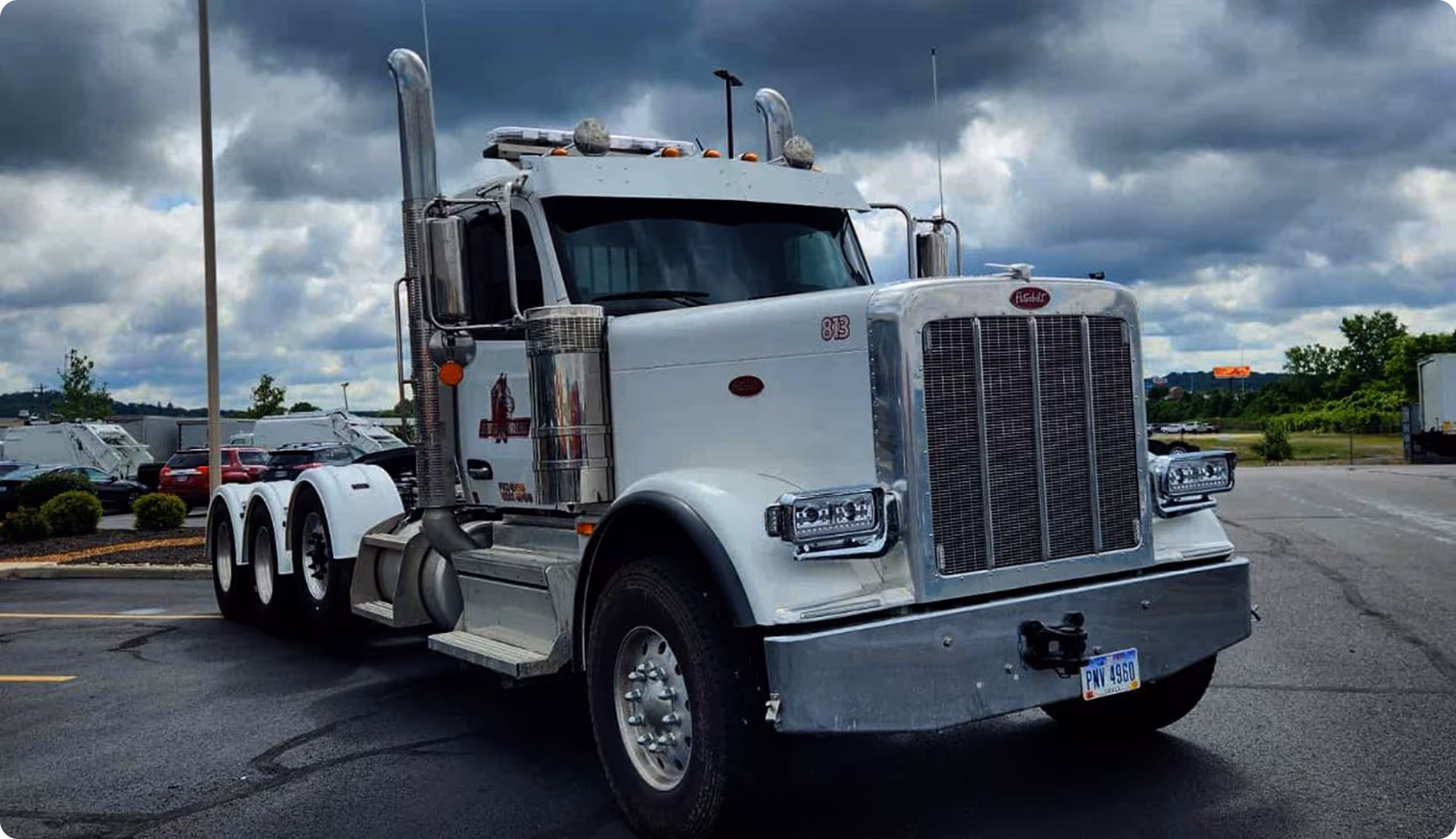 White Peterbilt semi-truck tractor parked in a lot under a cloudy sky.