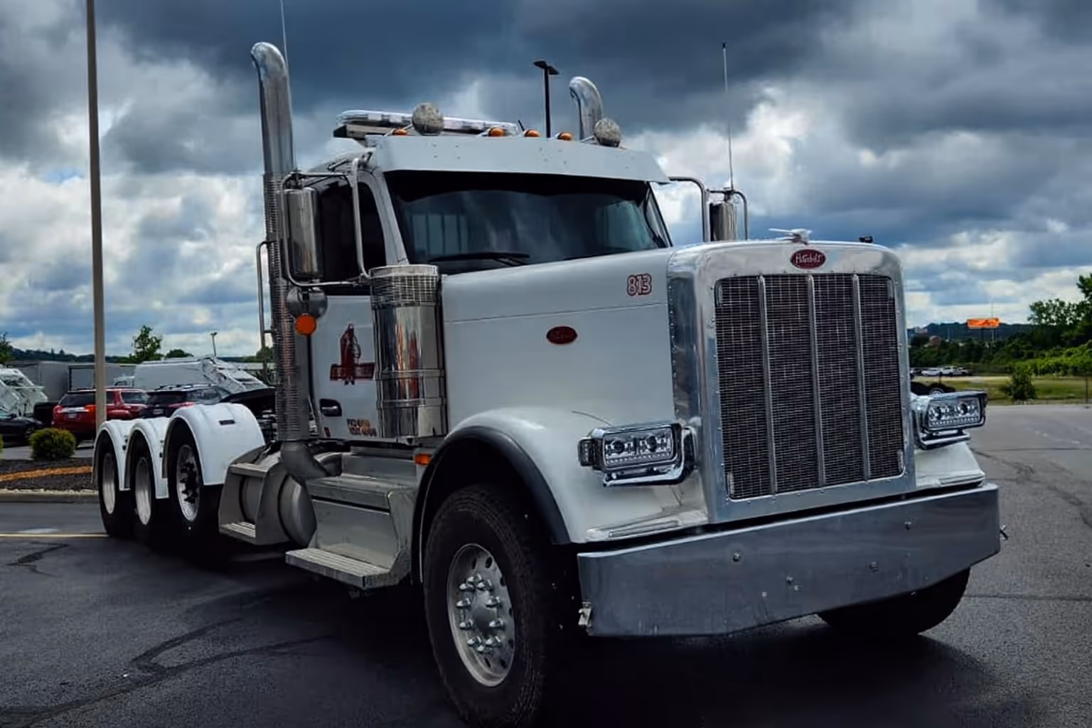 White Peterbilt semi truck parked on wet asphalt under a cloudy sky.