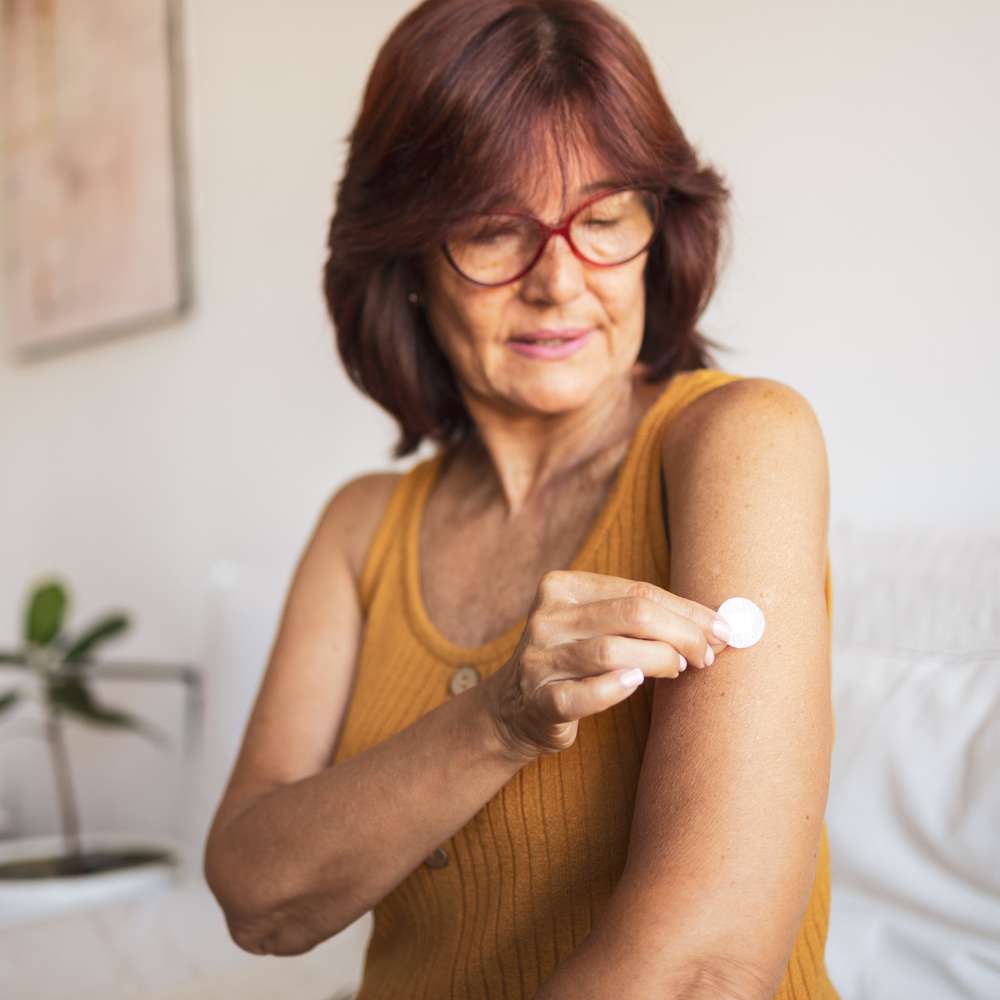Person placing a hormone wellness patch on the upper arm under professional guidance at Fanous Medspa in Charlotte, NC.