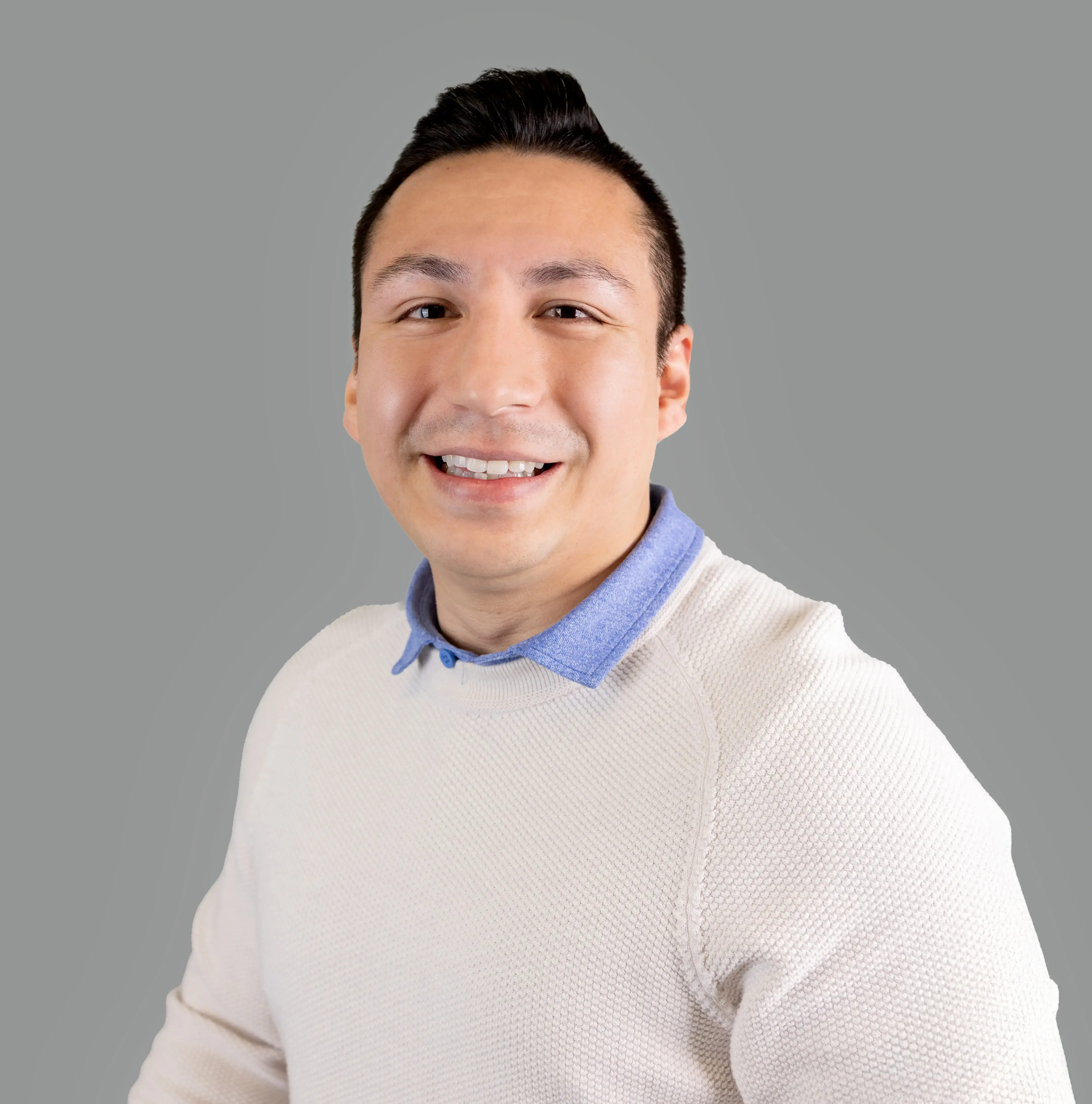 Smiling woman with long red hair wearing a maroon blazer and blue top in a modern office setting.