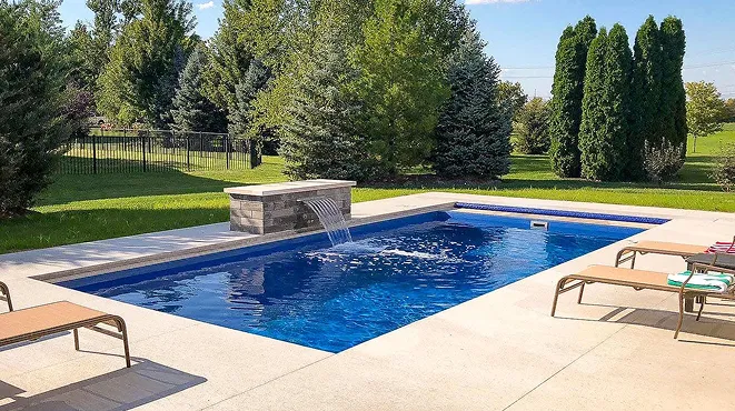A backyard with a pool and lounge chairs.