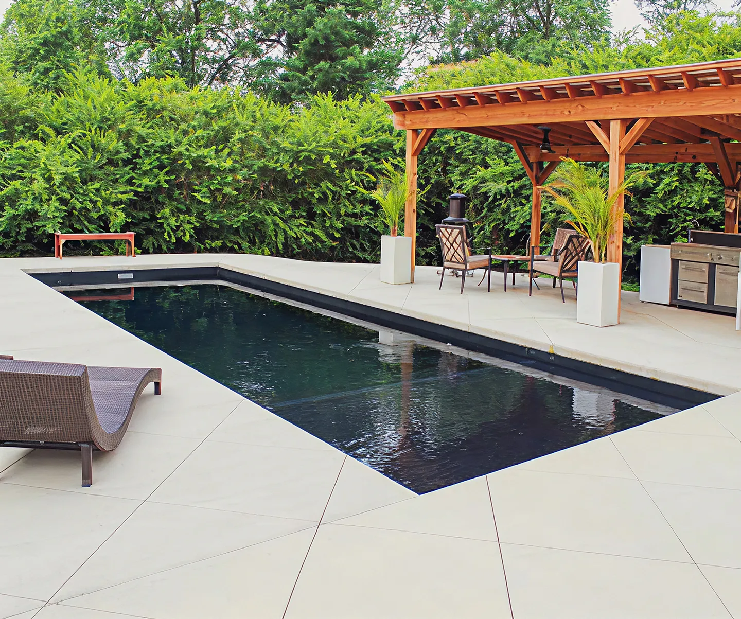 A patio with a pool and a grill.