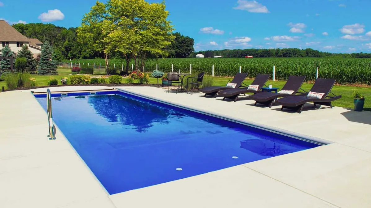 A large swimming pool with lounge chairs around it.