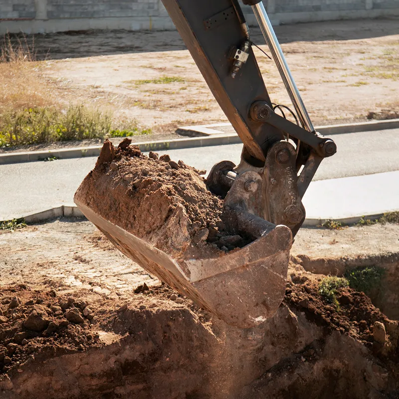 A bulldozer digging dirt on the side of a road.