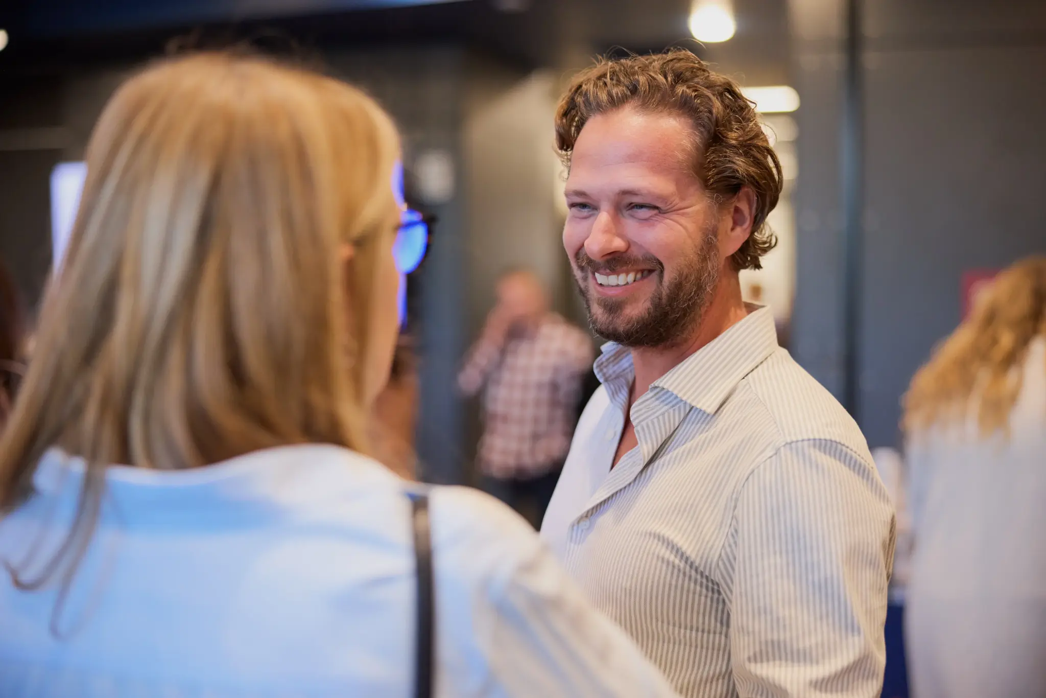 Man smiling while talking with a woman at a social gathering.