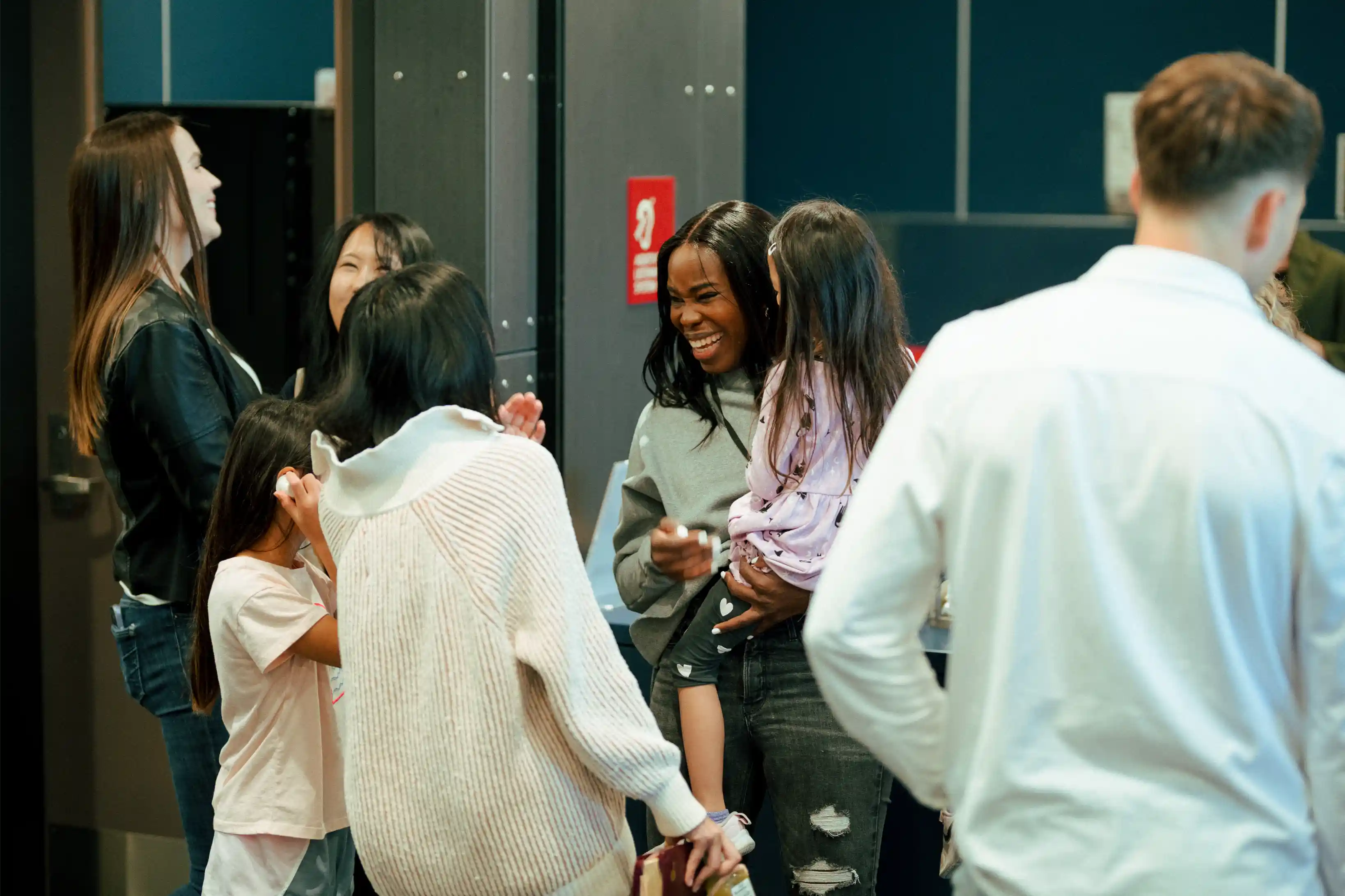 Group of people chatting and smiling inside a building lobby.