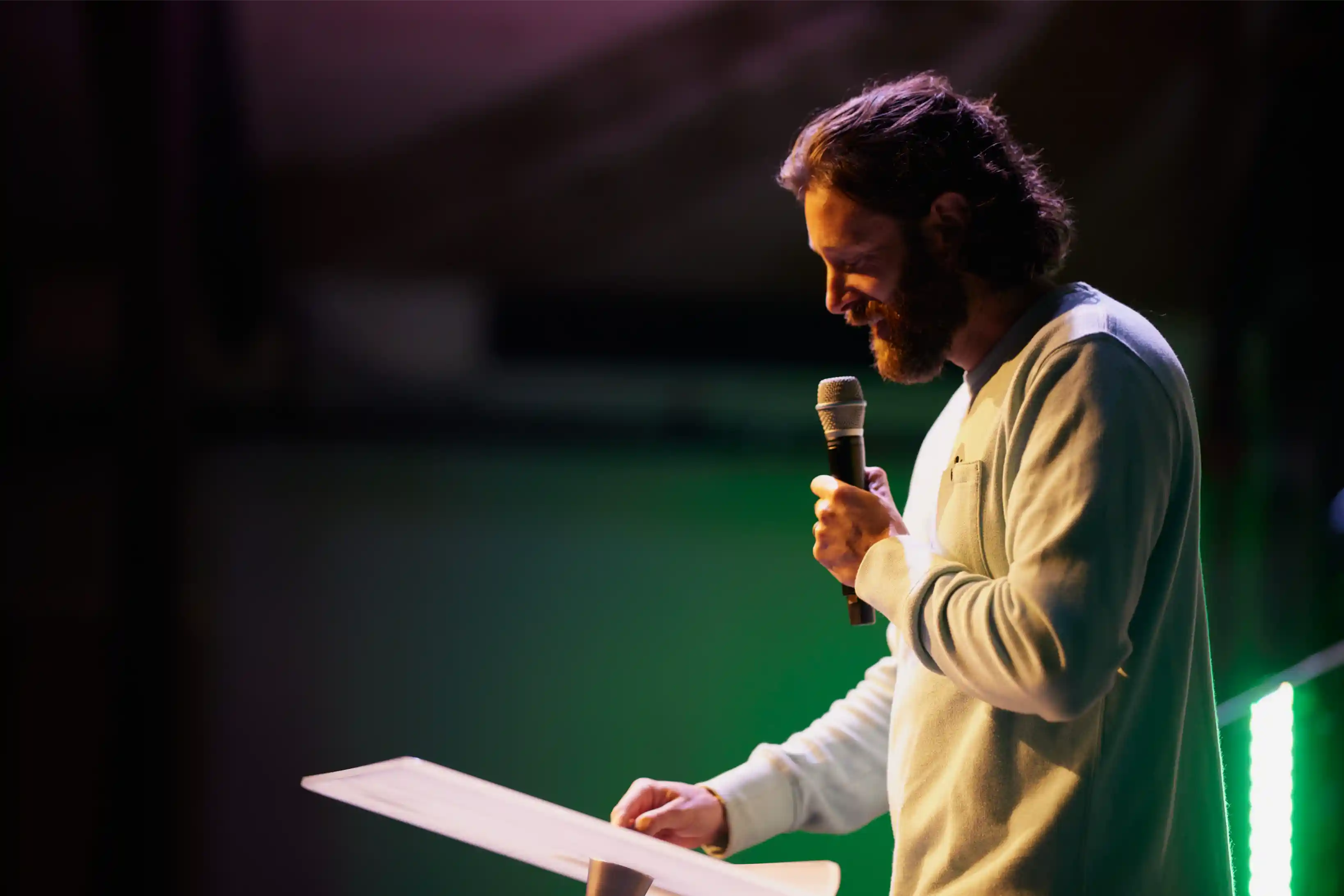 Speaker smiling while holding a microphone on stage.