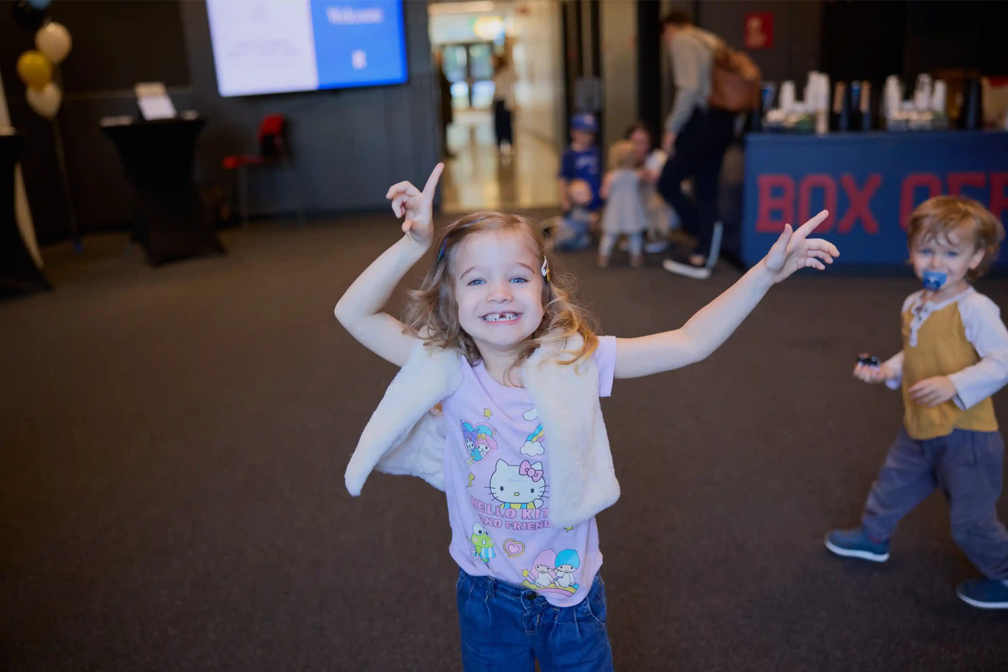 Happy child smiling and pointing in a welcoming indoor space.