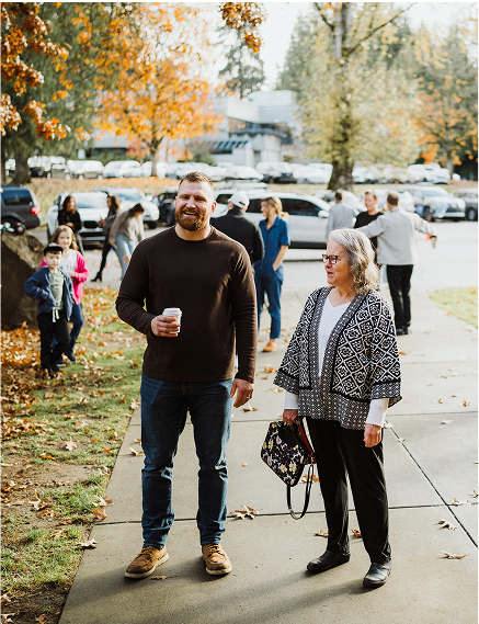People chatting outdoors on a sunny day with autumn leaves around.