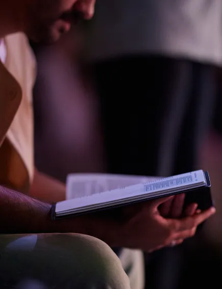 Person holding and reading a book, sitting with a focused posture.