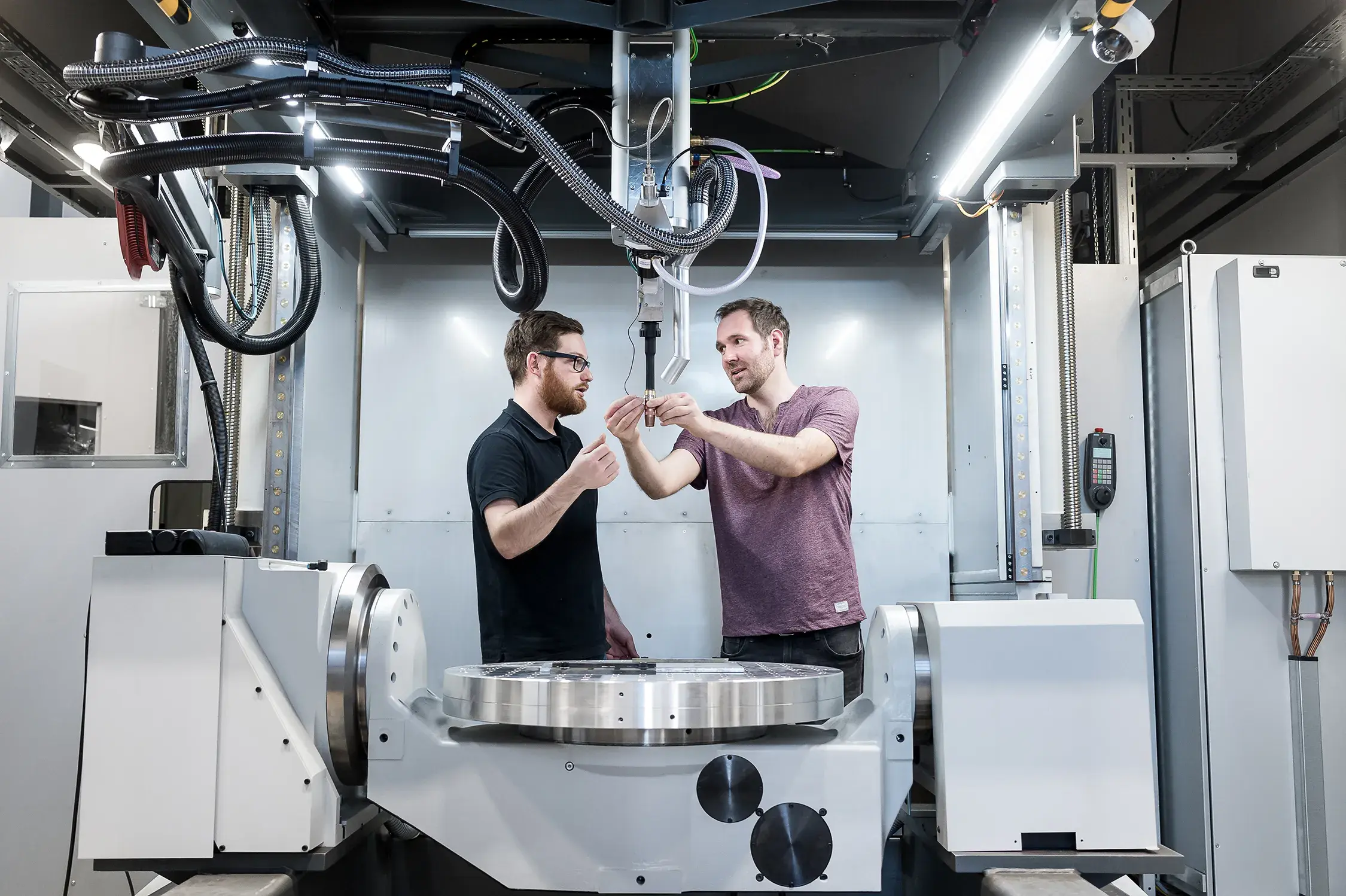 Zwei Männer sprechen und Arbeiten an einer Maschine.