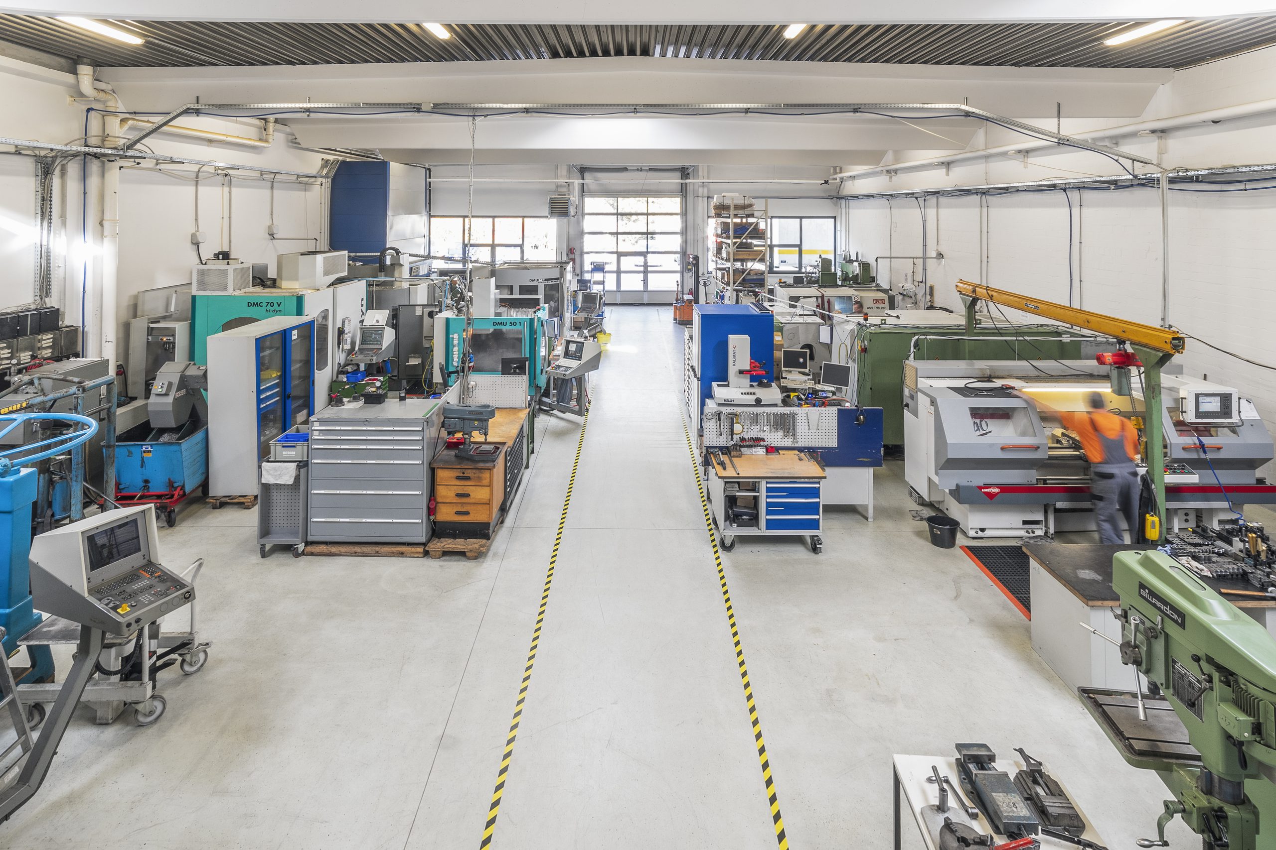 Produktionshalle mit mehreren Fertigungsstationen und Geräten.