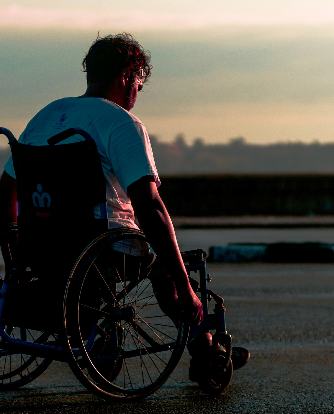 Seitlich abgebildete Person im Rollstuhl.