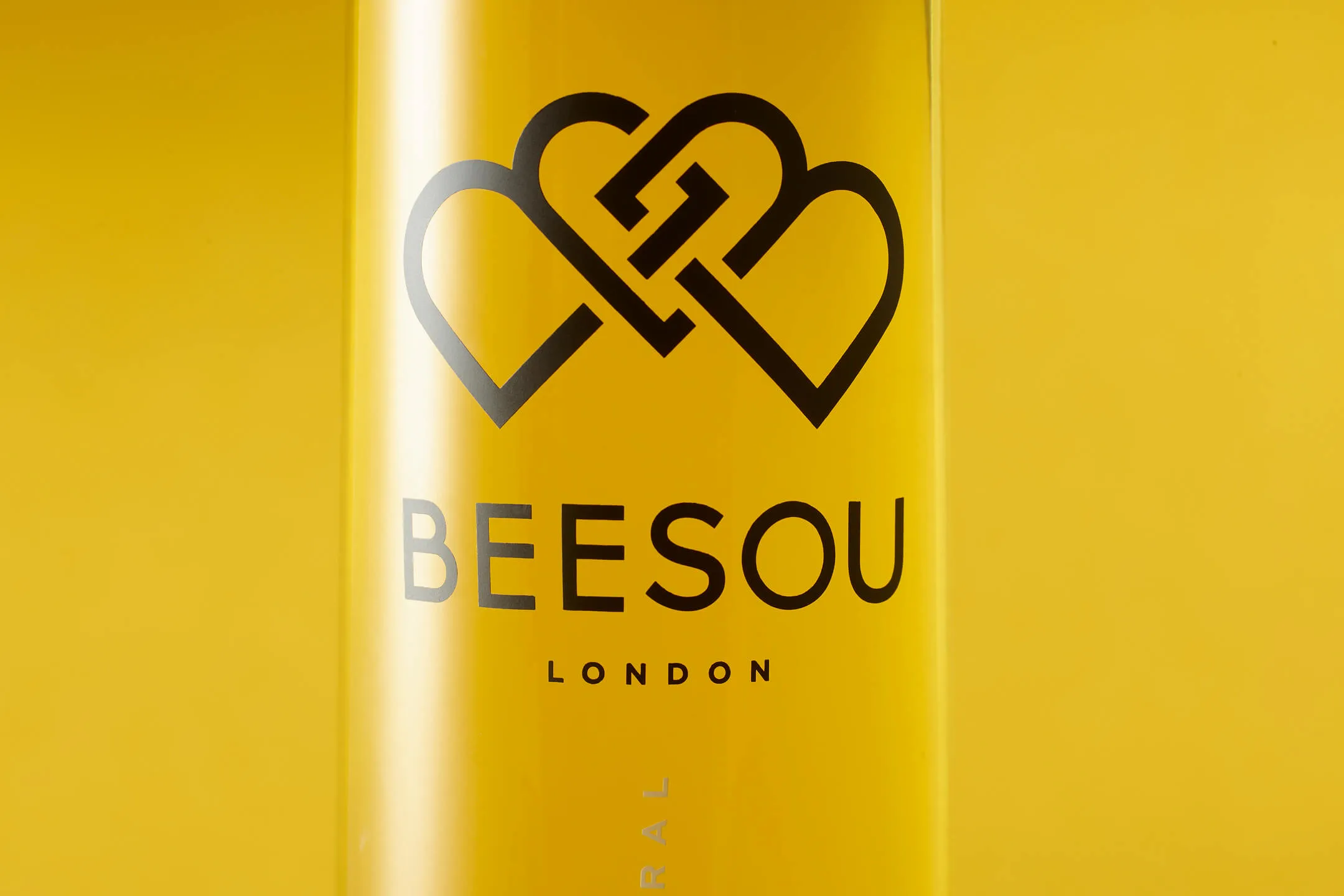 Yellow container with a black logo of two linked hearts and the text 'BEESOU LONDON'.