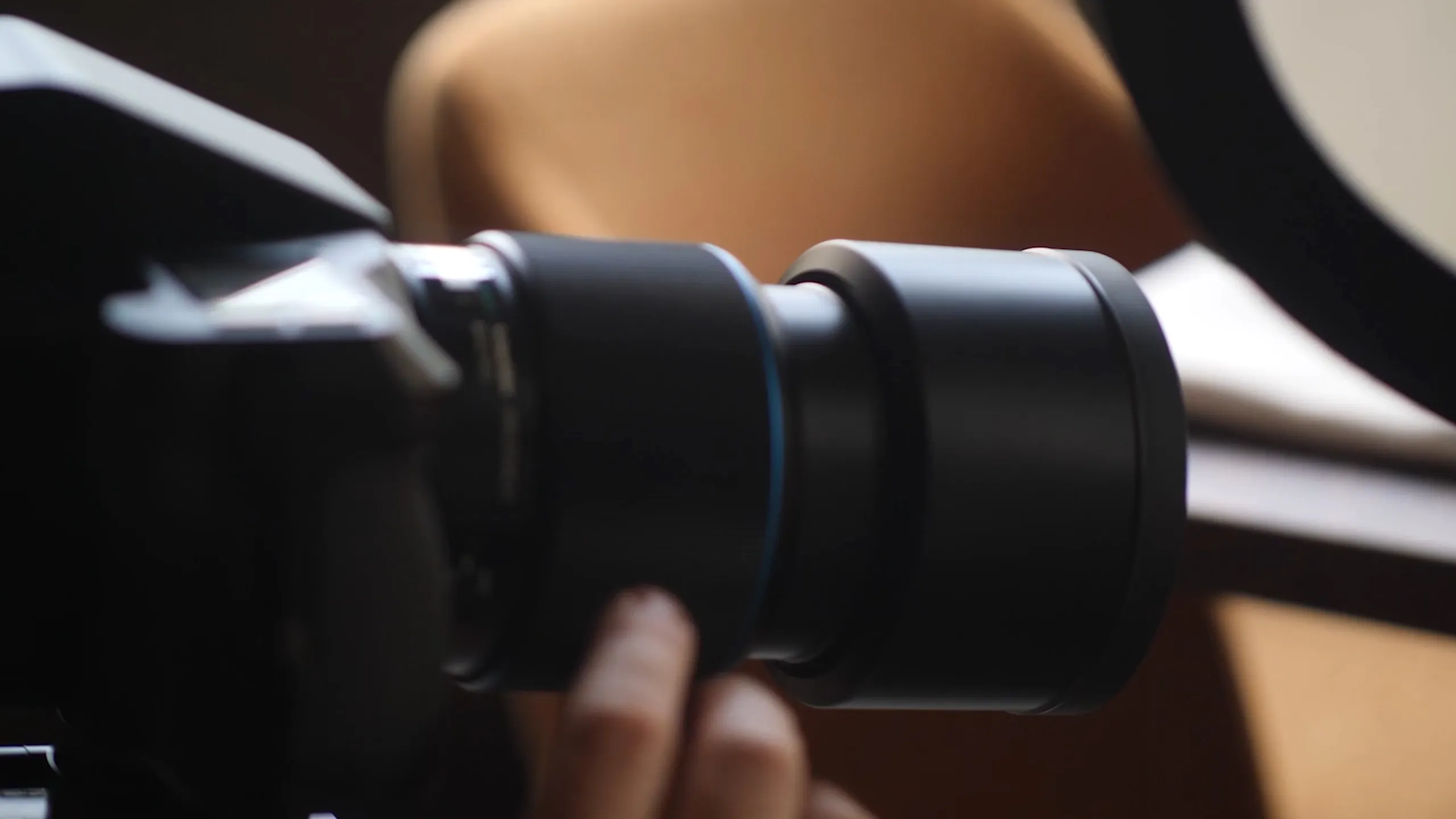 Close-up of a camera lens being adjusted by a person's fingers.